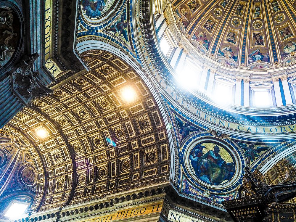 Ornate ceiling architecture in church with religious artwork, dome and light, St Peter's Basilica. Original public domain…