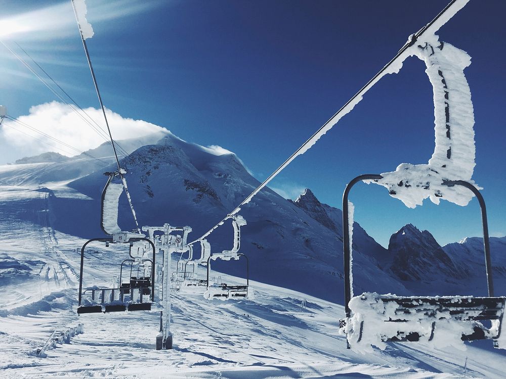 Snow covered ski lifts stopped on a snowy mountain. Original public domain image from Wikimedia Commons