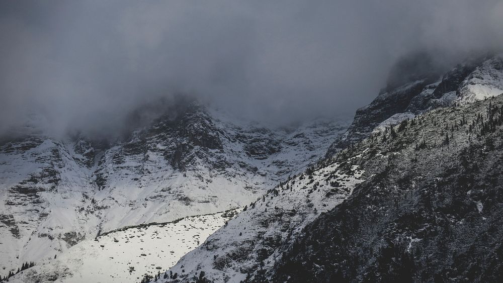 Clouds cover snowy mountains on a cold winter day. Original public domain image from Wikimedia Commons