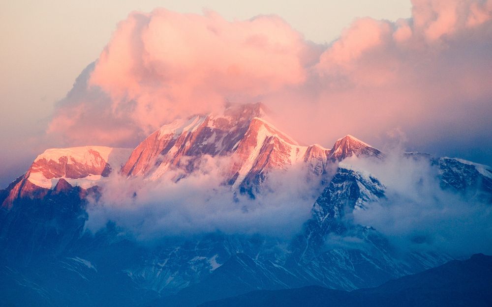 A snowy mountain bathed in pastel-colored light during sunset. Original public domain image from Wikimedia Commons