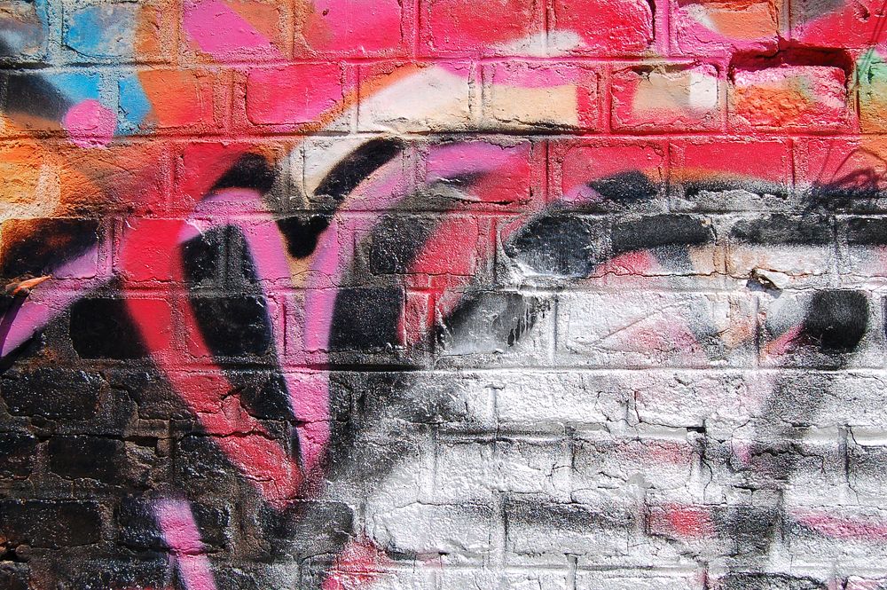 Grunge graffiti on brick wall behind colorful tables and chairs in Shoreditch. Original public domain image from Wikimedia…