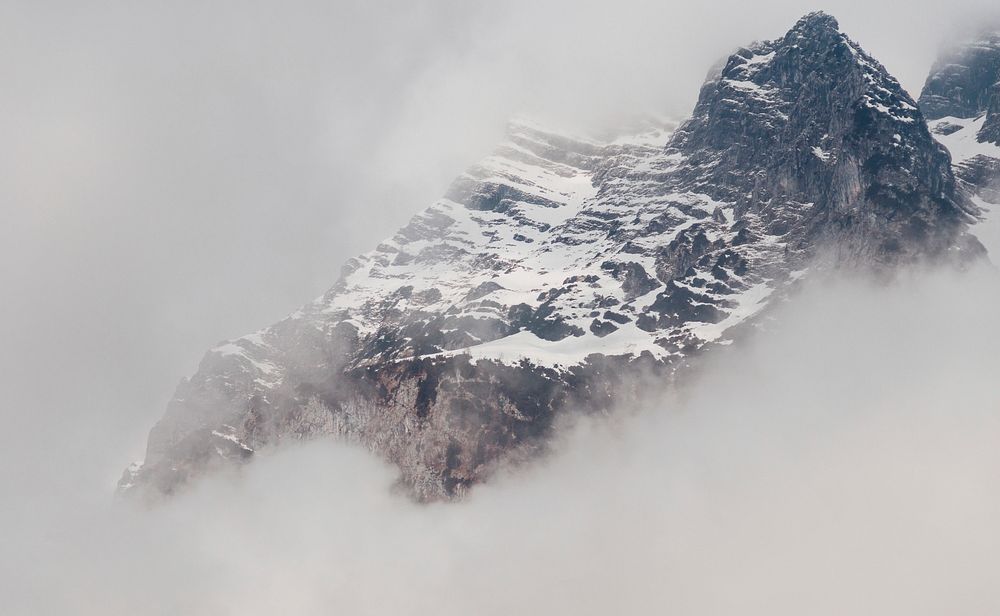 A snowy mountain partially obscured by a thick mist. Original public domain image from Wikimedia Commons