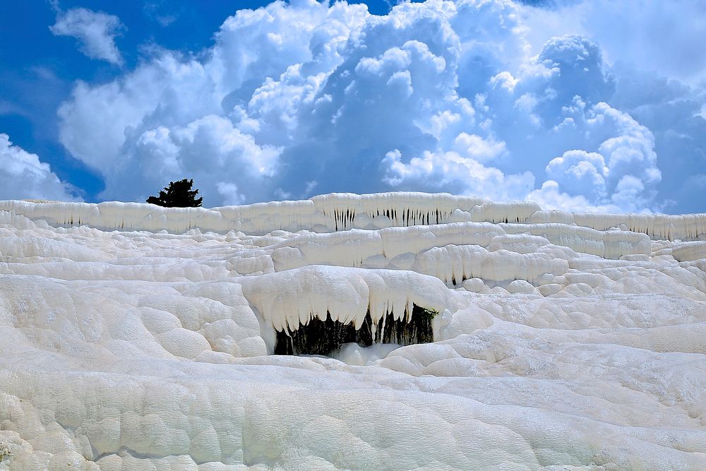 Layers of frozen snow touch blue sky filled with clouds in Hierapolis-Pamukkale. Original public domain image from Wikimedia…