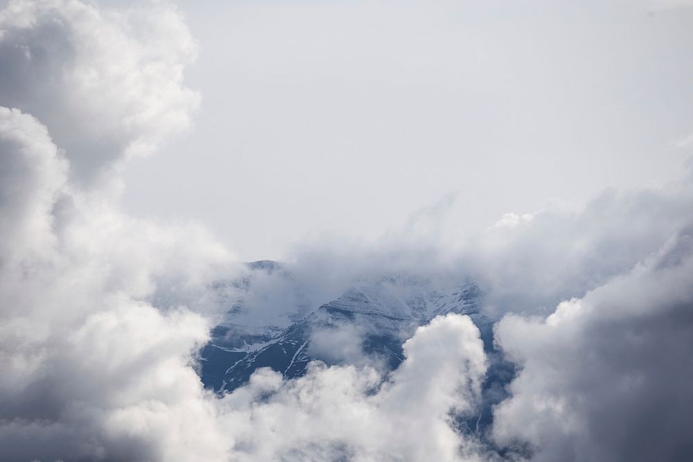 Clouds encompass the peak of a snowy mountain. Original public domain image from Wikimedia Commons