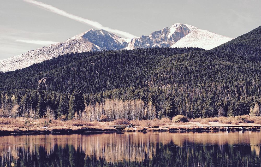 A long mountain ridge behind wooded hills near a lake in Estes Park. Original public domain image from Wikimedia Commons