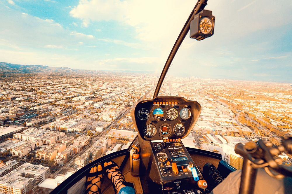 Inside the cockpit of a helicopter flying above a busy city downtown. Original public domain image from Wikimedia Commons