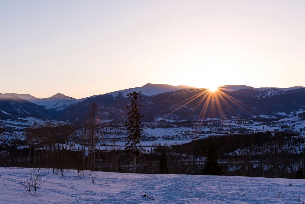 Setting sun diving behind a snow-covered mountain ridge in Silverthorne. Original public domain image from Wikimedia Commons