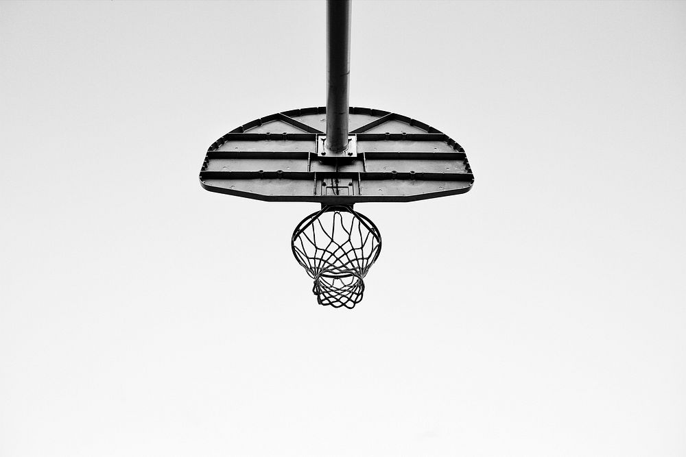 Black and white image taken underneath an outdoor basketball net. Original public domain image from Wikimedia Commons