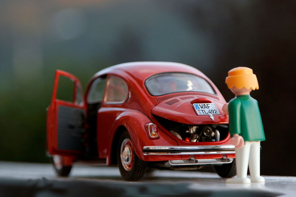 Playmobil toy red beetle with a woman pretending to go into the trunk. Original public domain image from Wikimedia Commons