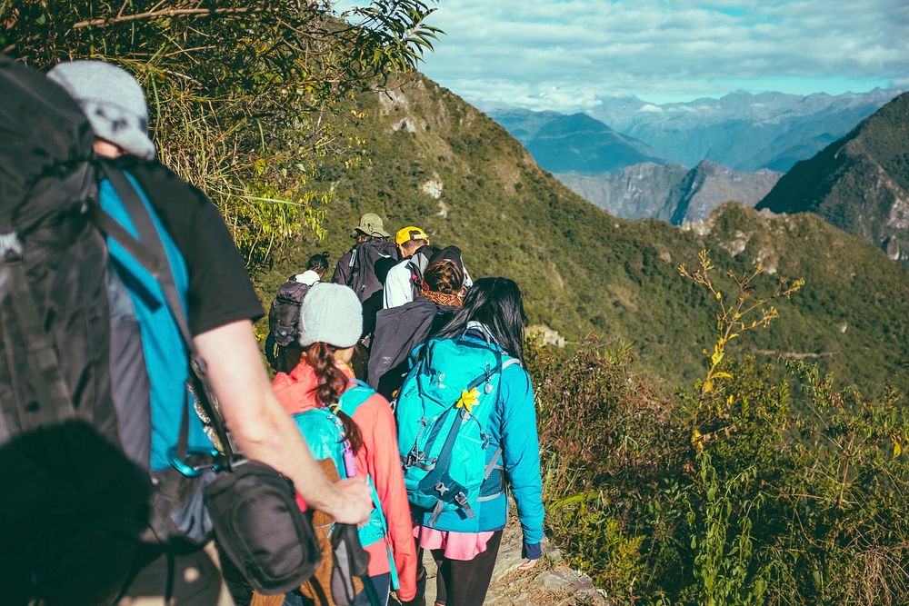 Group of hikers wearing backpacks and hiking gear walking up a mountain. Original public domain image from Wikimedia Commons