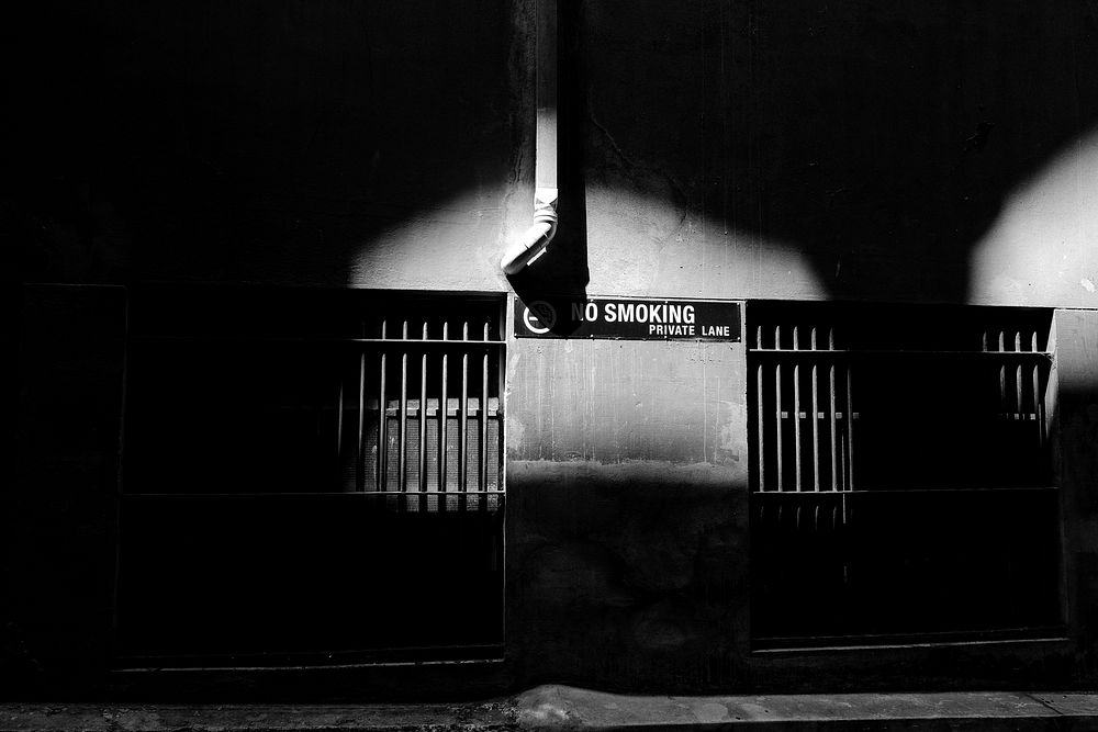A No Smoking sign is seen on a wall in a dark alley in Melbourne.. Original public domain image from Wikimedia Commons