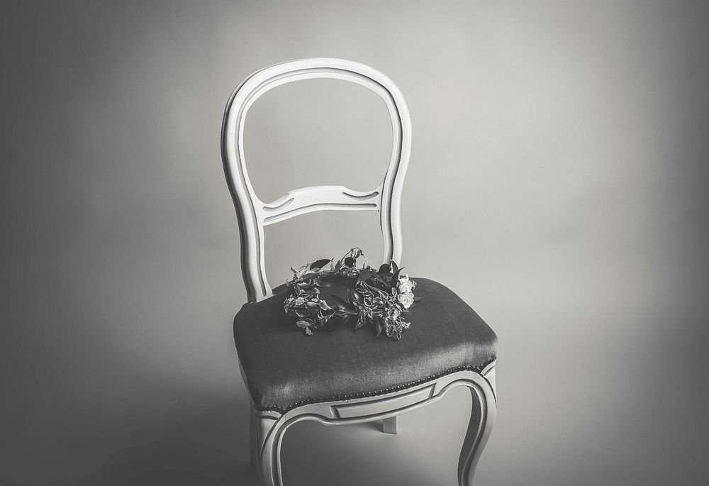 Black and white image of a vintage chair with a flower crown. Original public domain image from Wikimedia Commons
