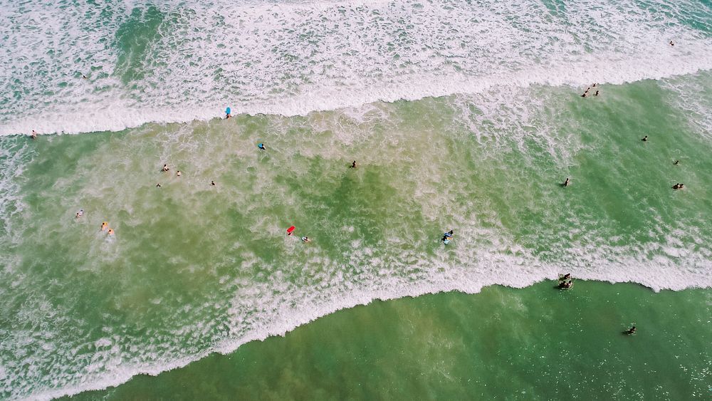 Drone aerial view of the people washed by the waves in shallow water at Cocoa Beach. Original public domain image from…