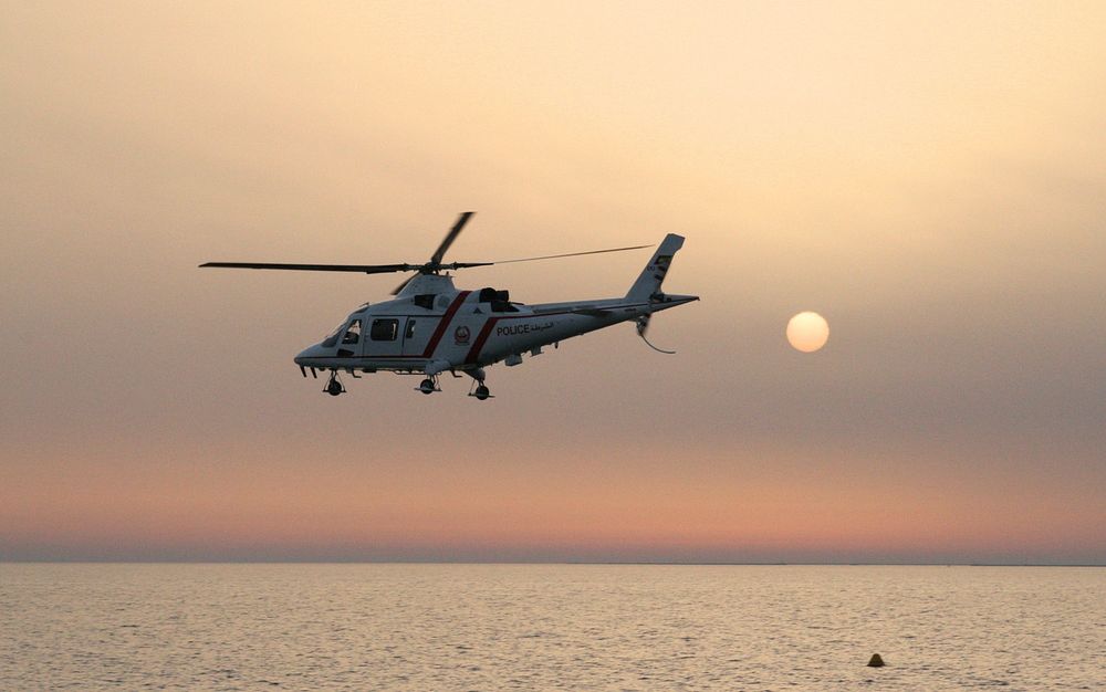 A helicopter flying over the water during sunset.. Original public domain image from Wikimedia Commons