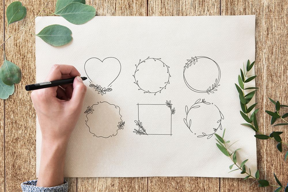 Artist designing vintage leafy frame set on a paper mockup