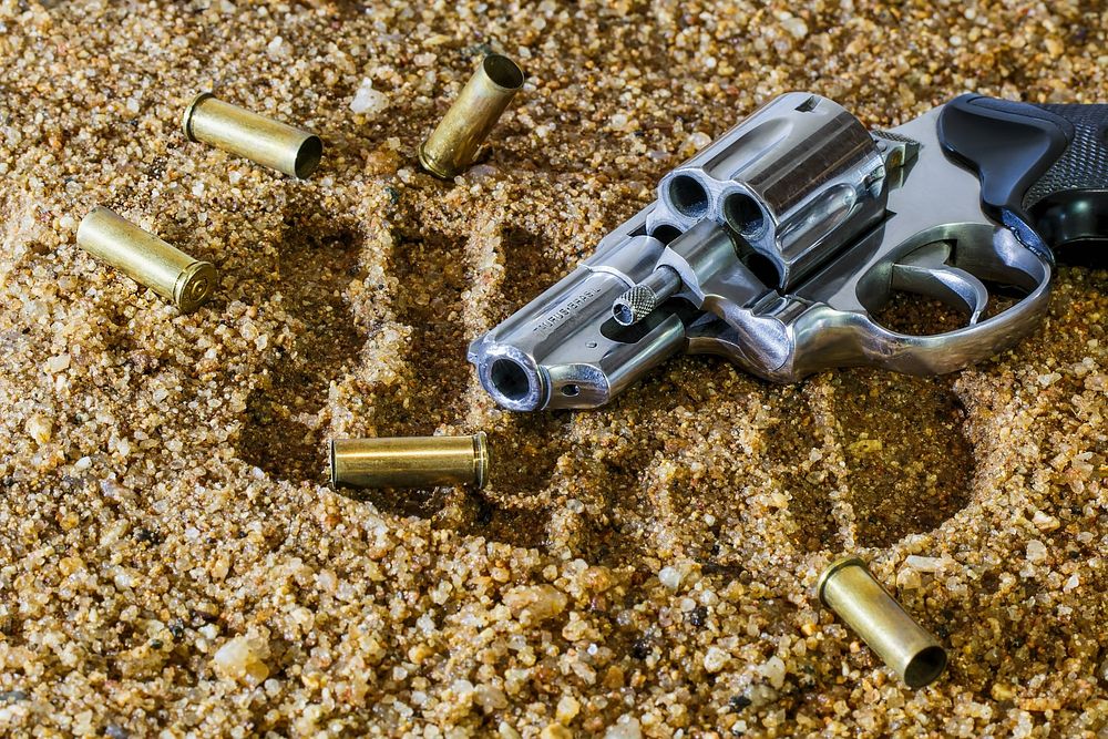 Free revolver with bullets on gravel photo, public domain weapon CC0 image.