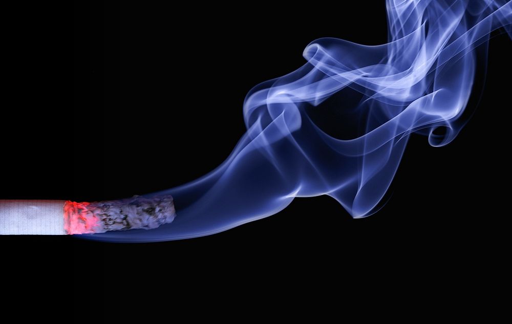 Free burning smoking cigarette on black background photo, public domain CC0 image.