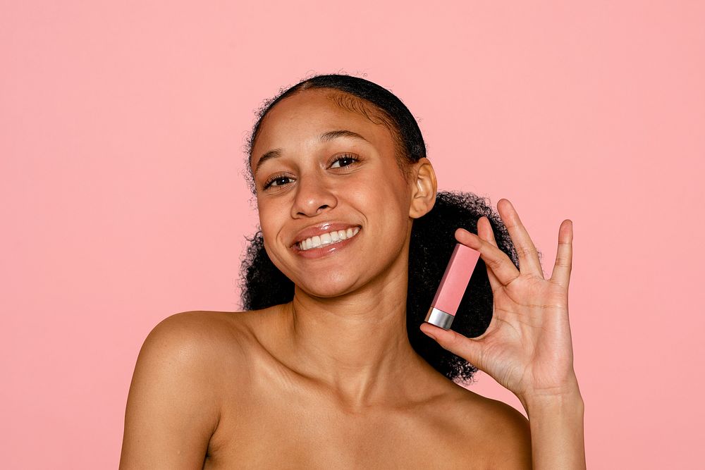 Young woman holding lipstick, makeup & cosmetics