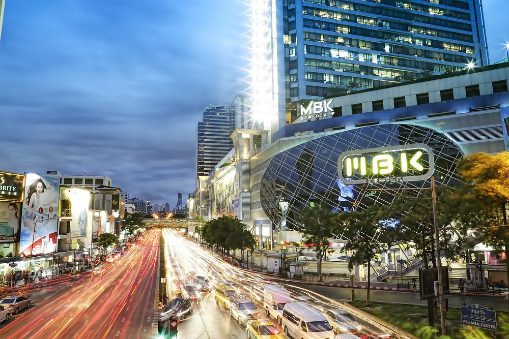 MBK Center at Pathum Wan intersection in Bangkok at night with light trails on Phaya Thai Road. Original public domain image…