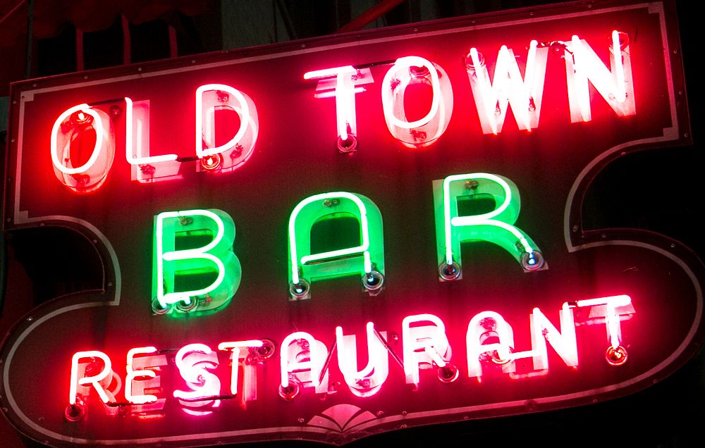 A bright red and green sign in a small town that shines at night.. Original public domain image from Wikimedia Commons
