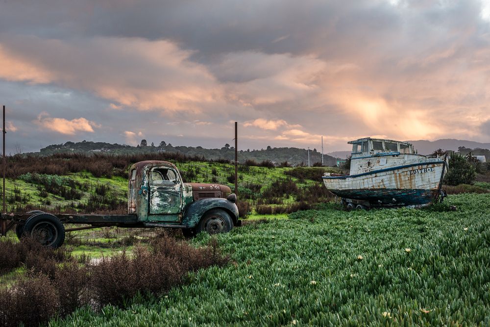 An old truck and a well-used boat (out of water) at the entryway to the Port Sonoma Marina in Petaluma, California.
