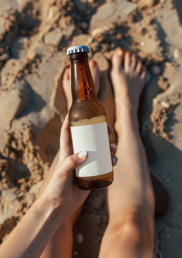 Woman holding a bottle of beer beverage barefoot outdoors.