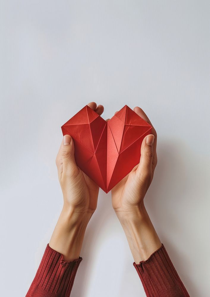 Hands holding paper red heart shape cosmetics perfume symbol.