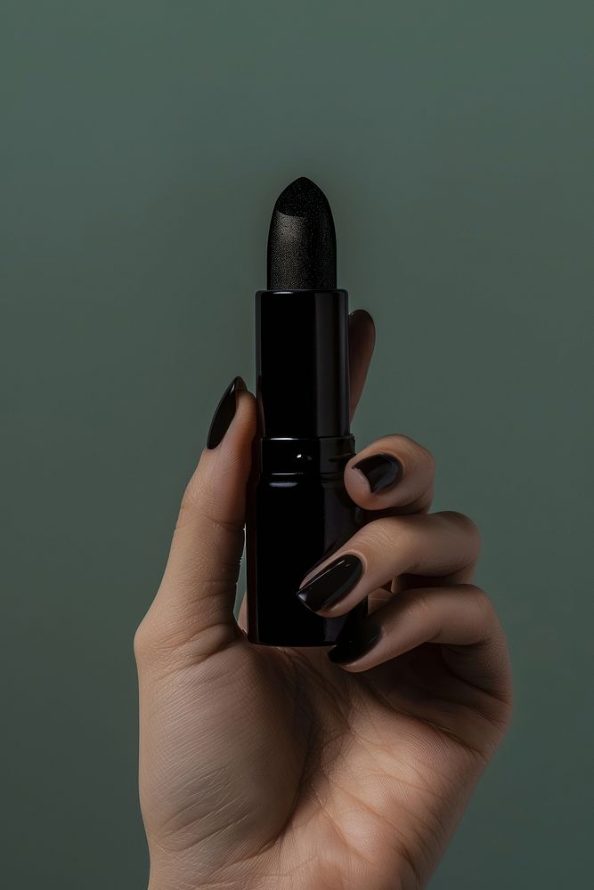 Vertical photo shot of a hand holding a black color lipstick cosmetics person human.