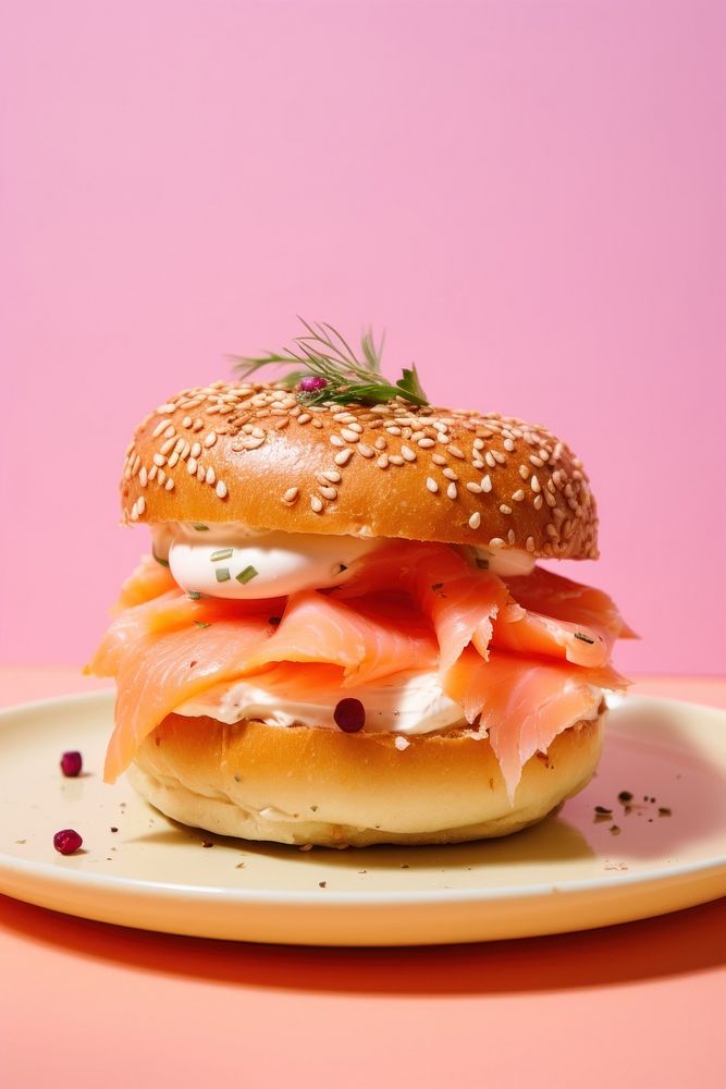 Bagel with creamcheese and salmon cut in half served on pink paper burger bread food.
