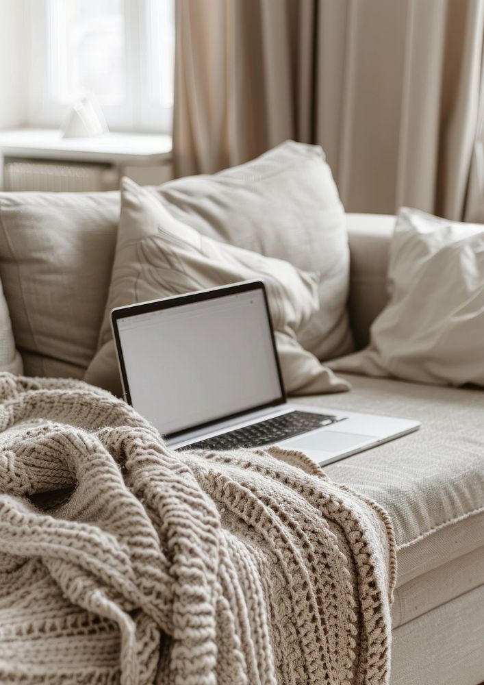 An open laptop on the sofa blanket couch electronics.