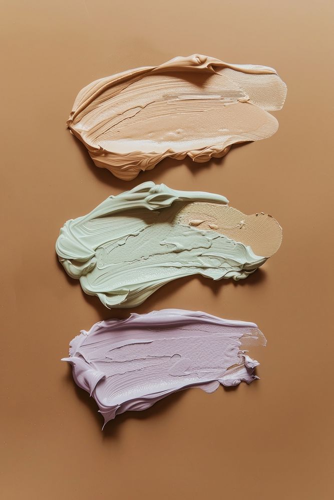 Liquid face foundation swatch in 4 shades of beige brown pale green and purple colors dessert diaper cream.