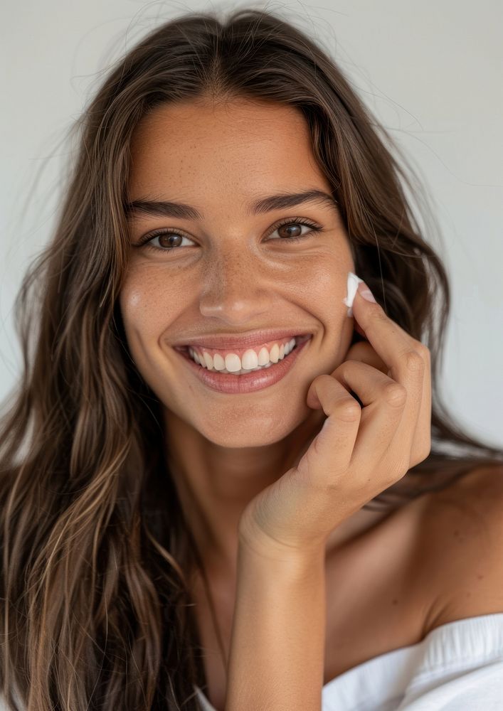 Woman applying cream on her face smile dimples person.