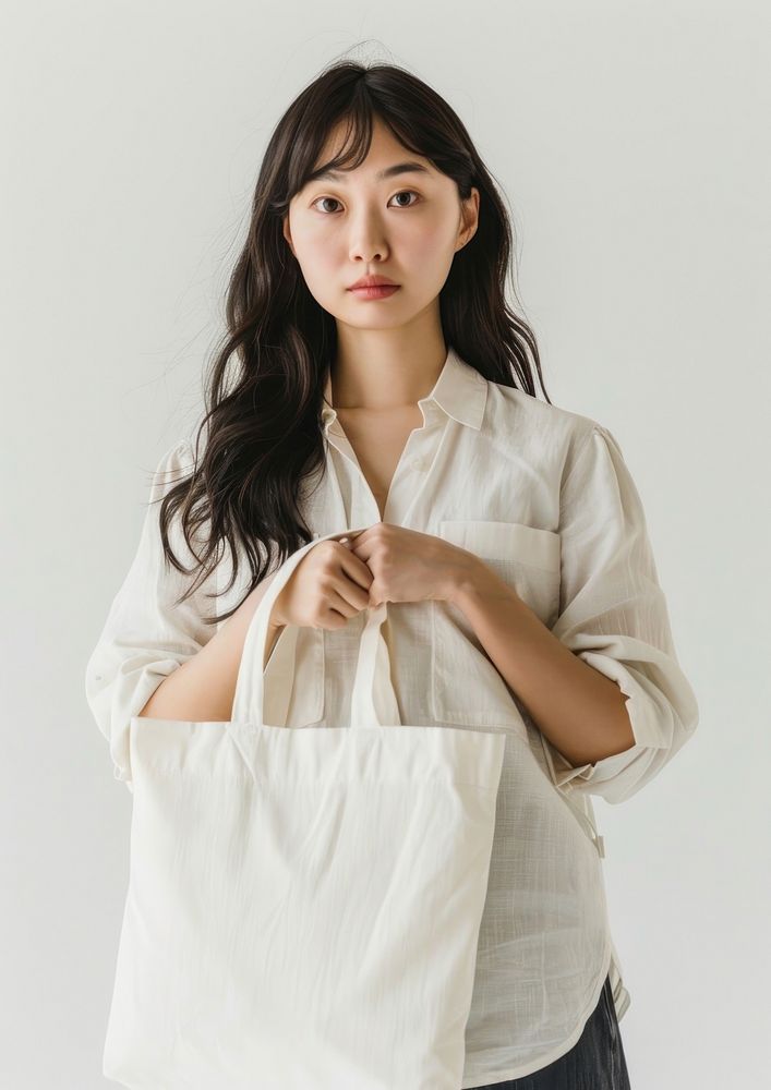 Asian woman in 50s wearing linen shirt holding a white tote bag mock up accessories accessory clothing.