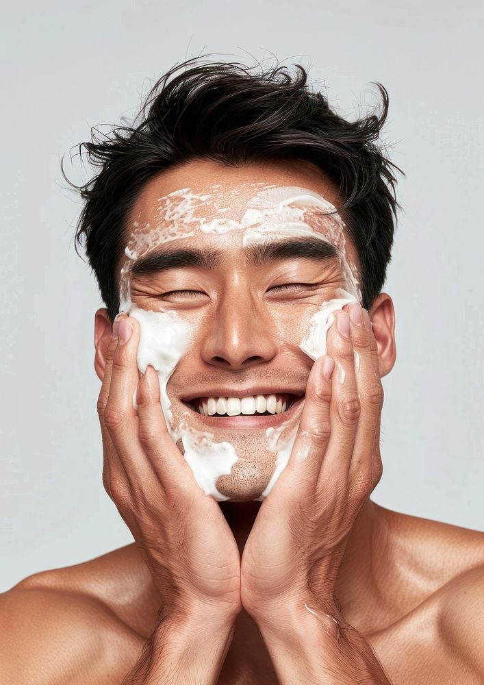 Asian man applying white facial scrubb to both cheeks washing person human.