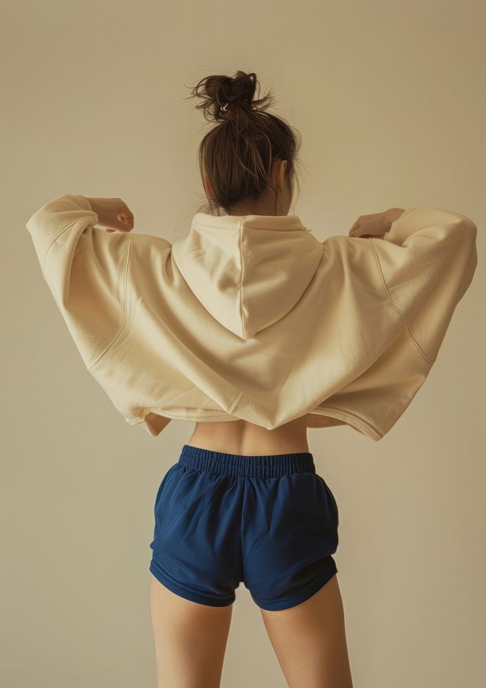 A woman wearing an oversized beige hoodie and blue shorts back clothing knitwear.