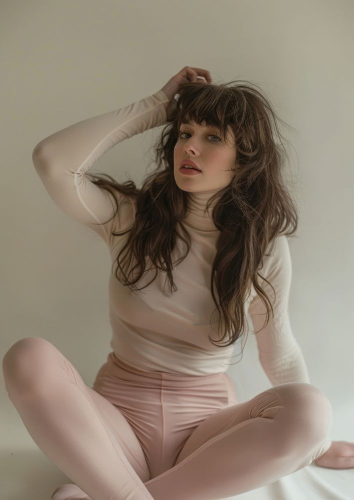 An attractive woman sitting on the floor wearing pink tights and a long-sleeved top photo face photography.