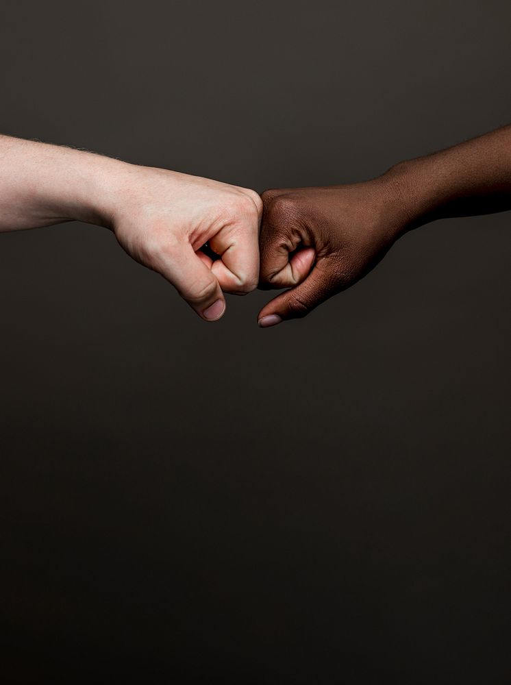 Close-up of a fist bump between diverse ethnic hands. Fist bump unity, friendship, and teamwork. Unity and friendship…