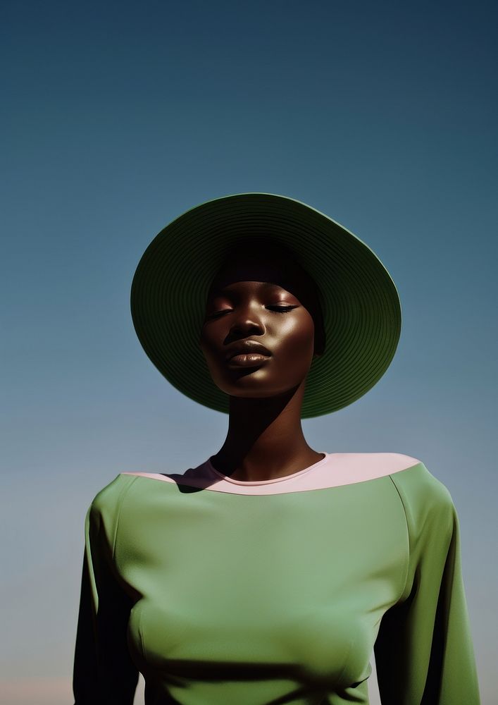 A black teenage woman face the sunlight wearing minimal green hat fashion adult portrait.