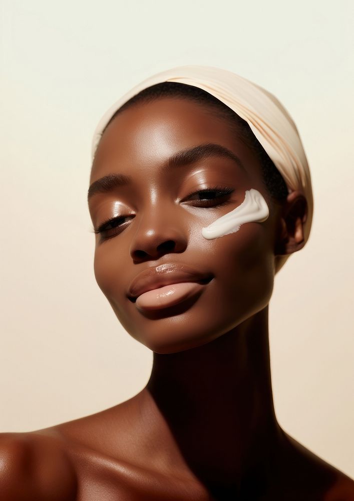 A black woman apply a skincare cream on her face photography portrait fashion.