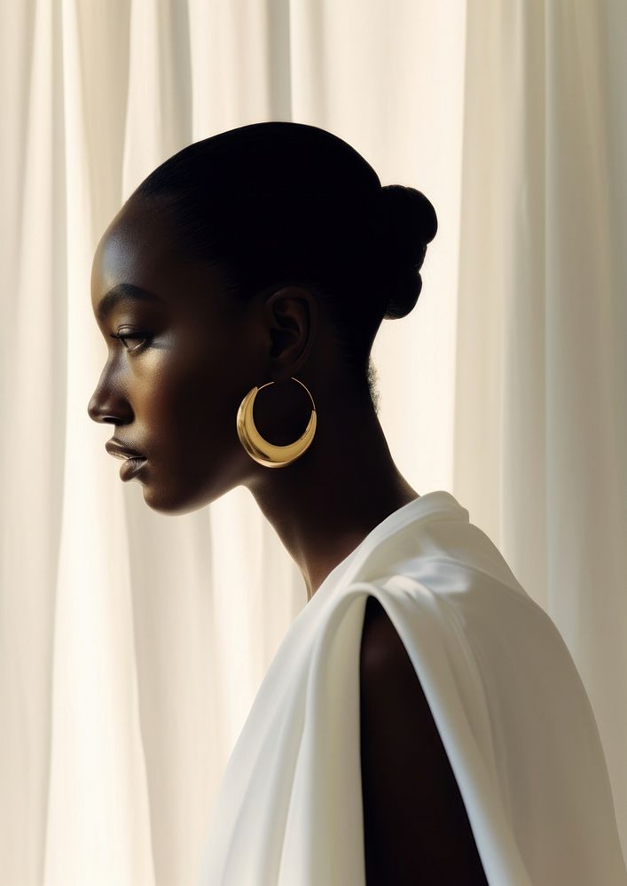 A black woman poke her head out of the white curtains wearing modern gold earring photography portrait jewelry.