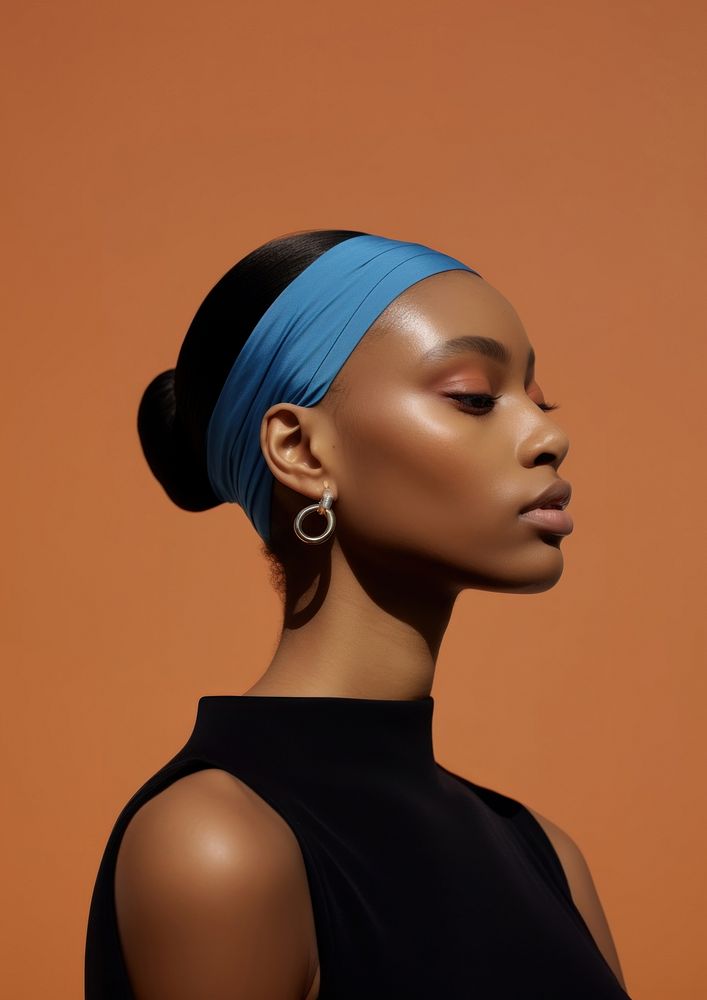 A black woman wearing blue eyeliner with modern brown headband photography portrait earring.