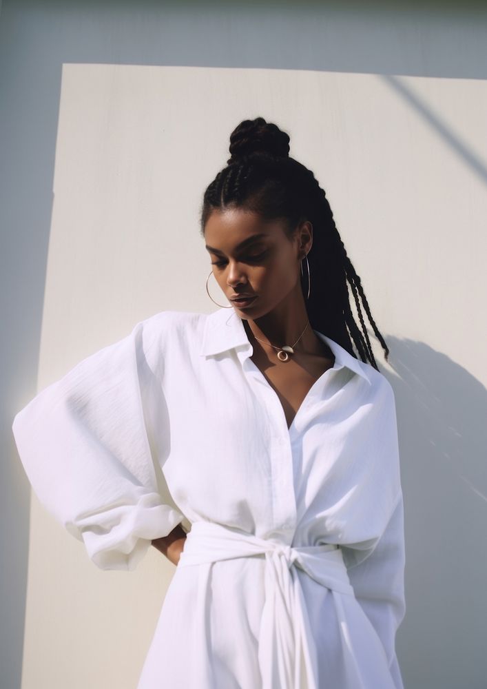 A black woman wearing white modern minimal cloth and modern hairstyle fashion adult contemplation.