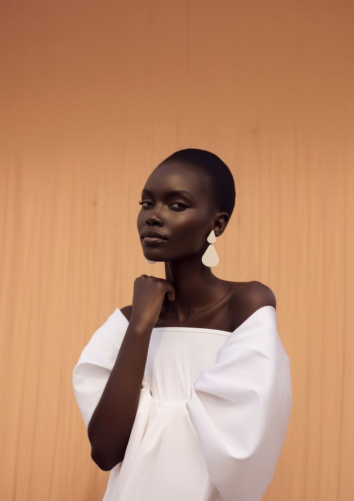 A black woman wearing white minimal dress and white minimal earring fashion adult hairstyle.