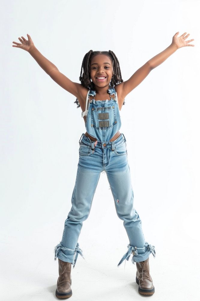 A young girl stands with arms joyfully raised denim cheerful footwear.