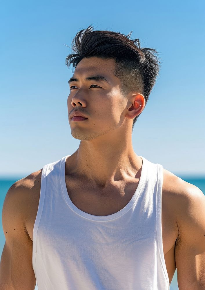 Asian man wearing white tank top beach contemplation tranquility.
