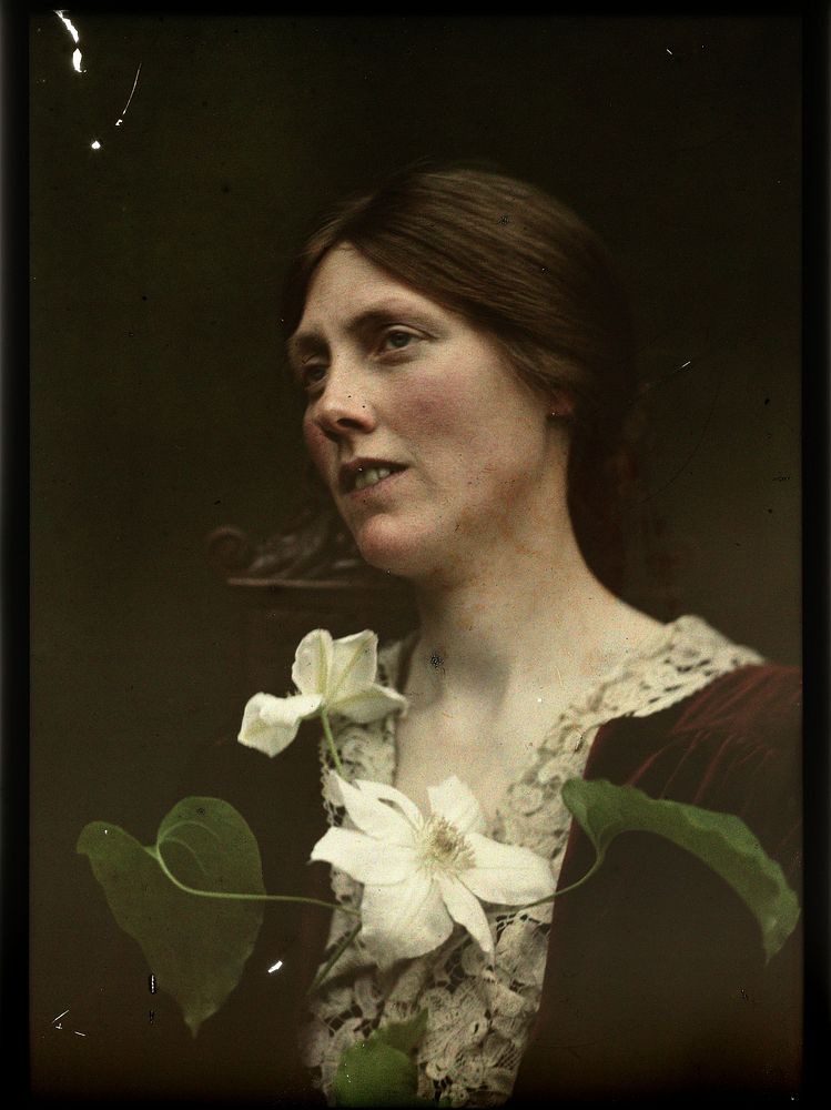 Portret van een vrouw gekleed in een rode jurk met twee witte bloemen voor haar borst (1907 - 1930) by anonymous