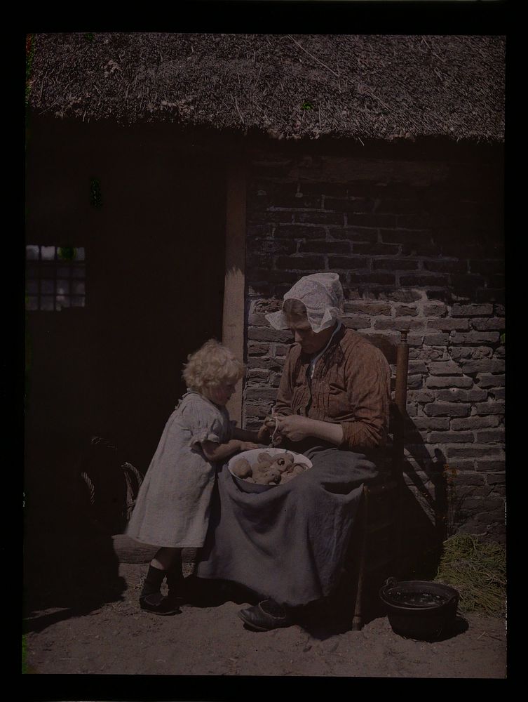 Vrouw schilt aardappelen, een kind kijkt toe (c. 1907 - c. 1935) by anonymous