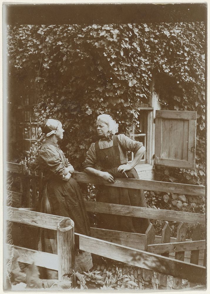 Twee buurvrouwen in gesprek bij een tuinhek, Leeuwarden (c. 1900 - c. 1910) by anonymous and Knackstedt and Näther