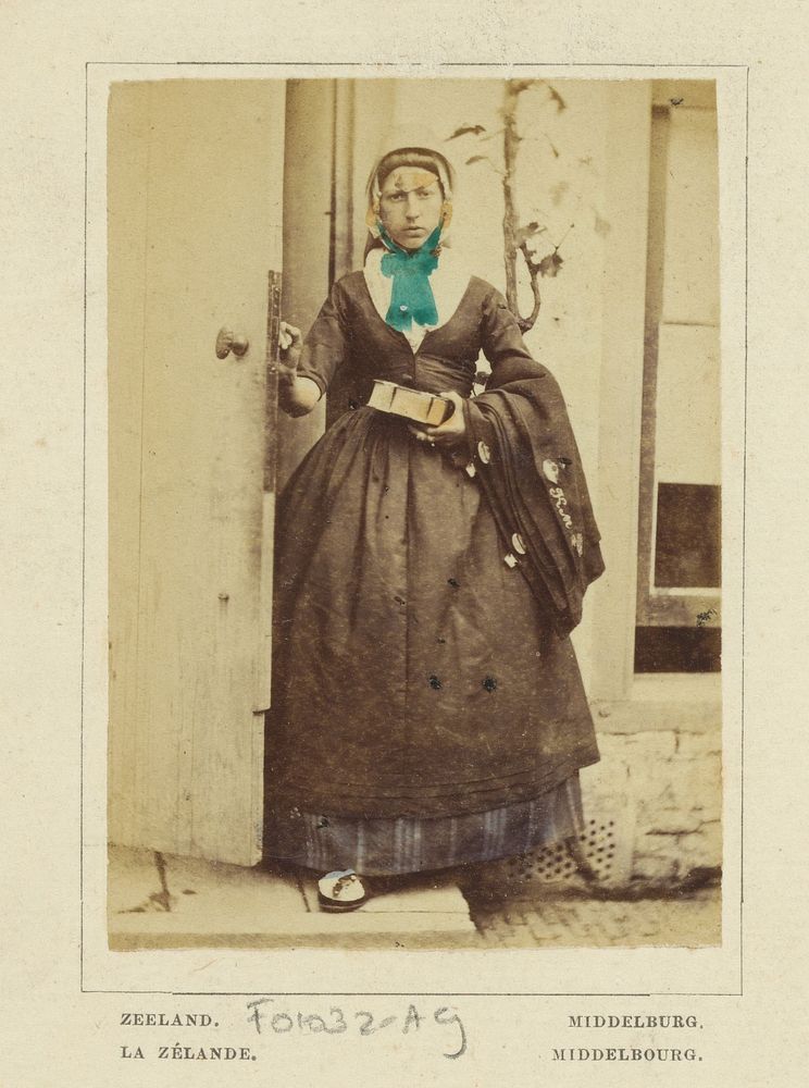 Portret van een onbekende vrouw met fotoalbum of boek in klederdracht van Middelburg, Zeeland (1860 - 1890) by Andries Jager…