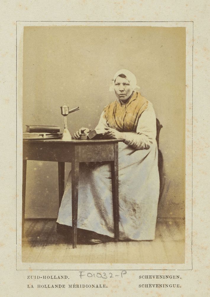 Portret van een onbekende vrouw met fotoalbums of boeken in klederdracht van Scheveningen, Zuid-Holland (1860 - 1890) by…